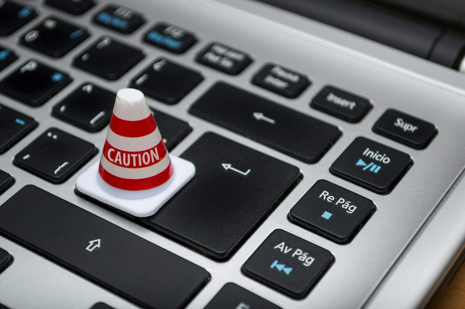 Caution warning cone placed on a laptop keyboard, symbolizing data risk and security concerns when using digital tools and AI chatbots.