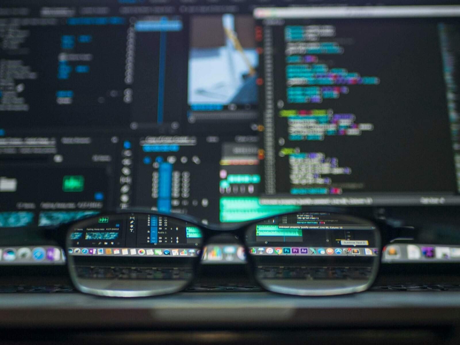 Eyeglasses in front of a computer screen displaying code and data dashboards, representing visibility and control of data in AI chatbot systems.