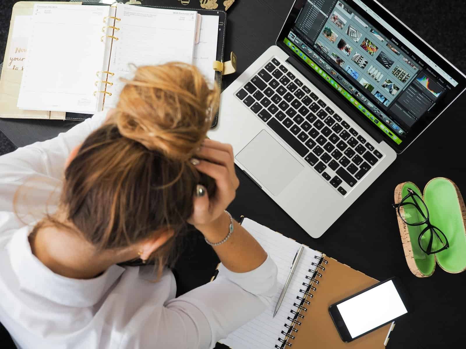 Overhead view of a real estate professional working on a laptop with notebooks and smartphone, analyzing lead conversion and pipeline data.