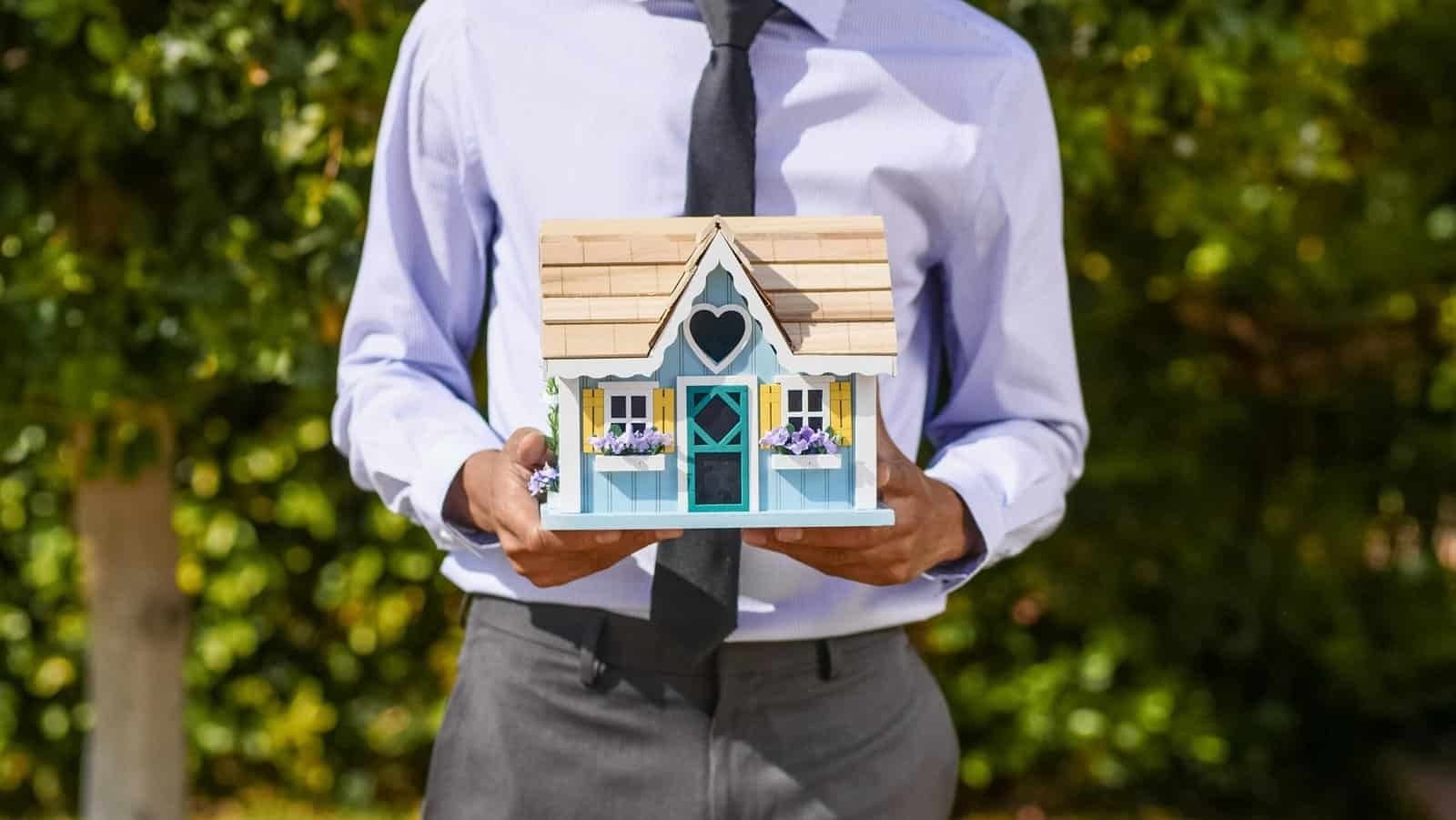Real estate professional holding a house model representing real estate lead automation and AI conversational chatbot solutions